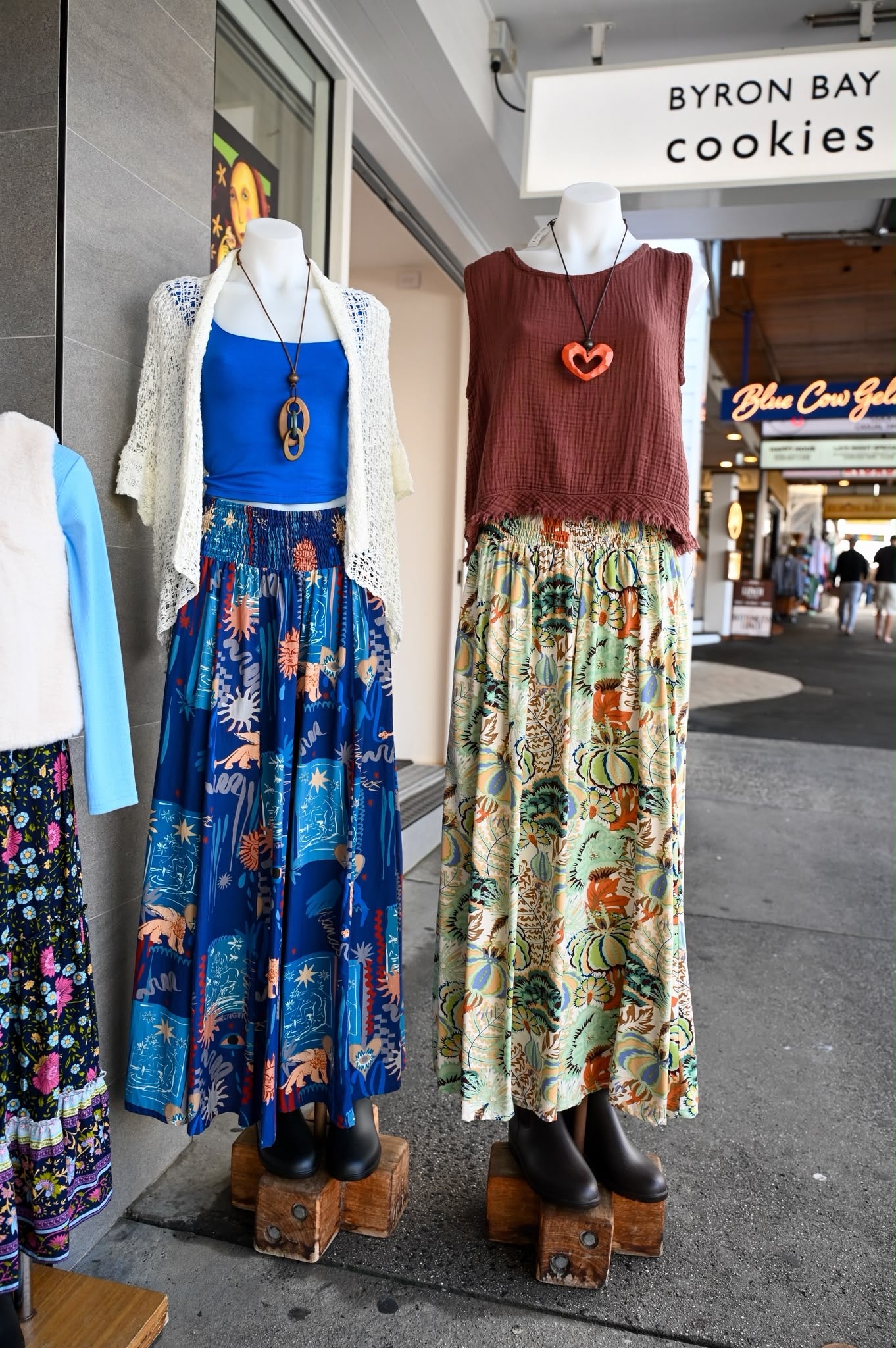 Two bohemian-style mannequin outfits displayed on wooden pedestals outside a storefront. The left outfit features the Byron Pant Wanderlust Navy. 
