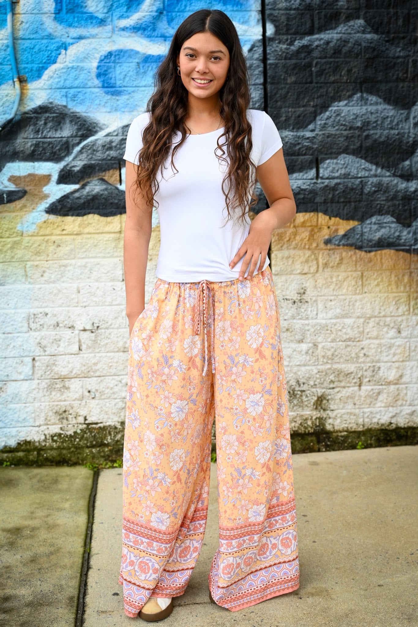 A woman wearing a white t-shirt Meli Lounge Pants Sunrise Botanica.