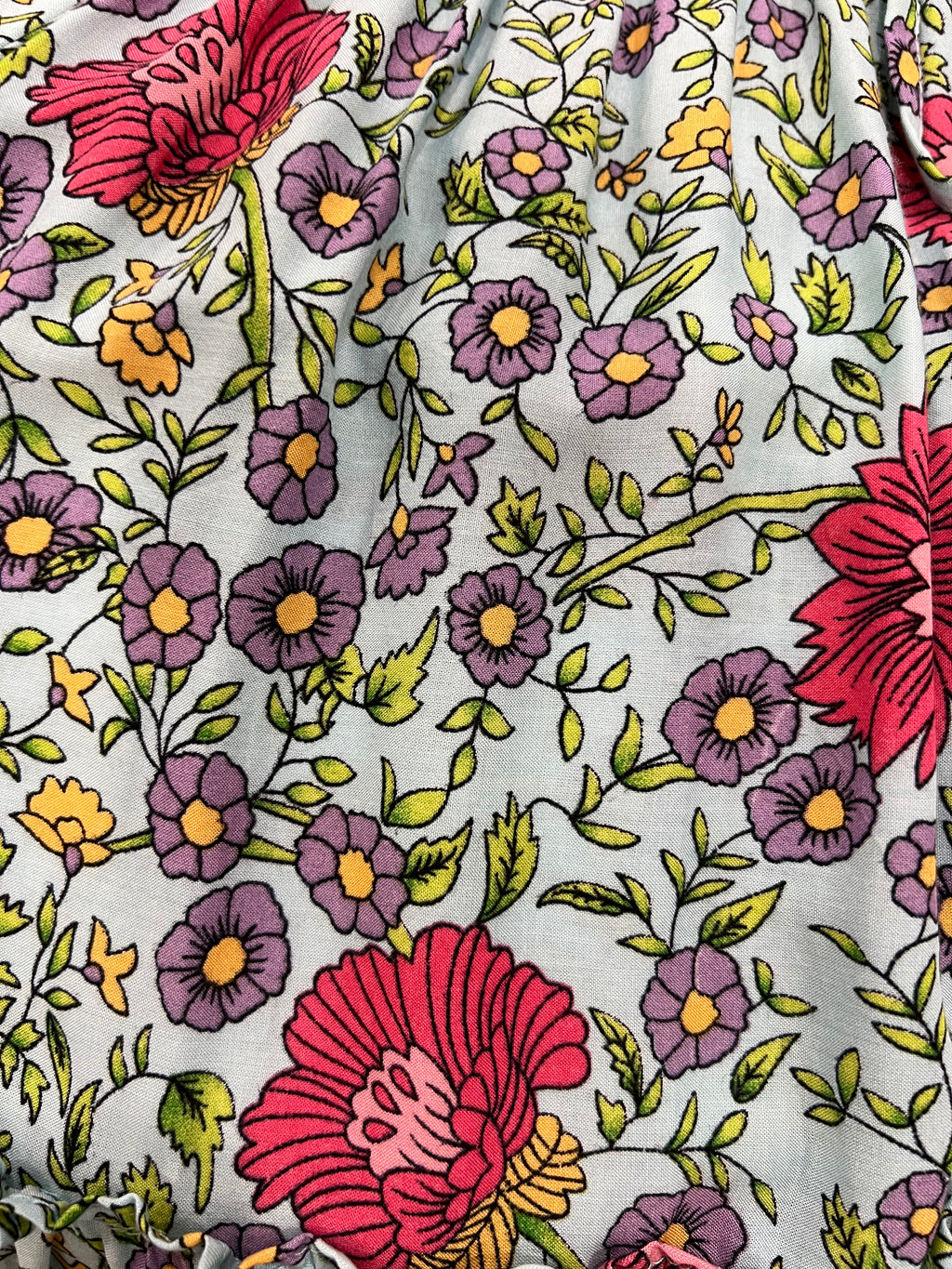 A close-up of a Aqua Wildflower print, a aqua blue floral fabric print featuring large red flowers, purple daisies, and green leaves.
