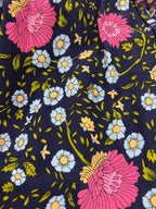 A close-up of Maeve Indigo Wildflower print, a dark navy floral fabric with large pink flowers, small light blue daisies with yellow centers, and green leaves and stems.
