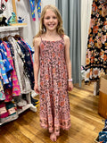 A young girl with blonde hair stands barefoot in a clothing store, wearing a sleeveless, MilaMeli Aria Spring Dress Blush Widflower Print.