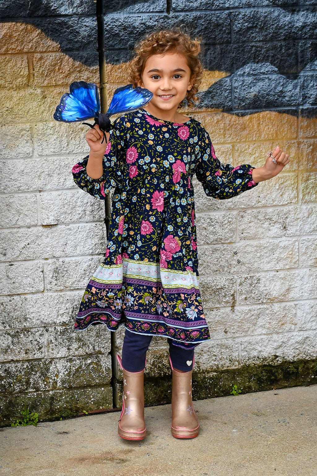 A young girl with curly light brown hair wearing Lotte Dress Indigo Wildflower top.