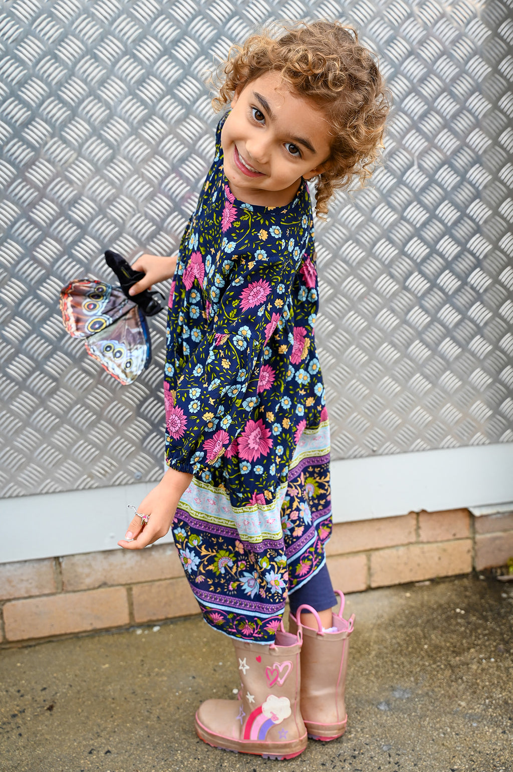 A young girl with curly light brown hair wearing Lotte Dress Indigo Wildflower top.
