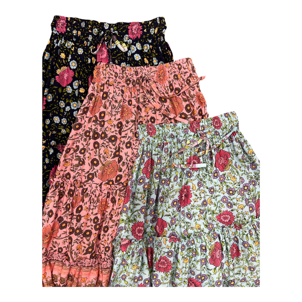 Three pairs of women's tiered ruffle shorts with floral prints, stacked diagonally. The top is Maeve Maxi Skirt Indigo Wildflower and the middle is the Maeve Maxi Skirt blush pink print, the bottom is Maeve Maxi Skirt Indigo Wildflower Print.