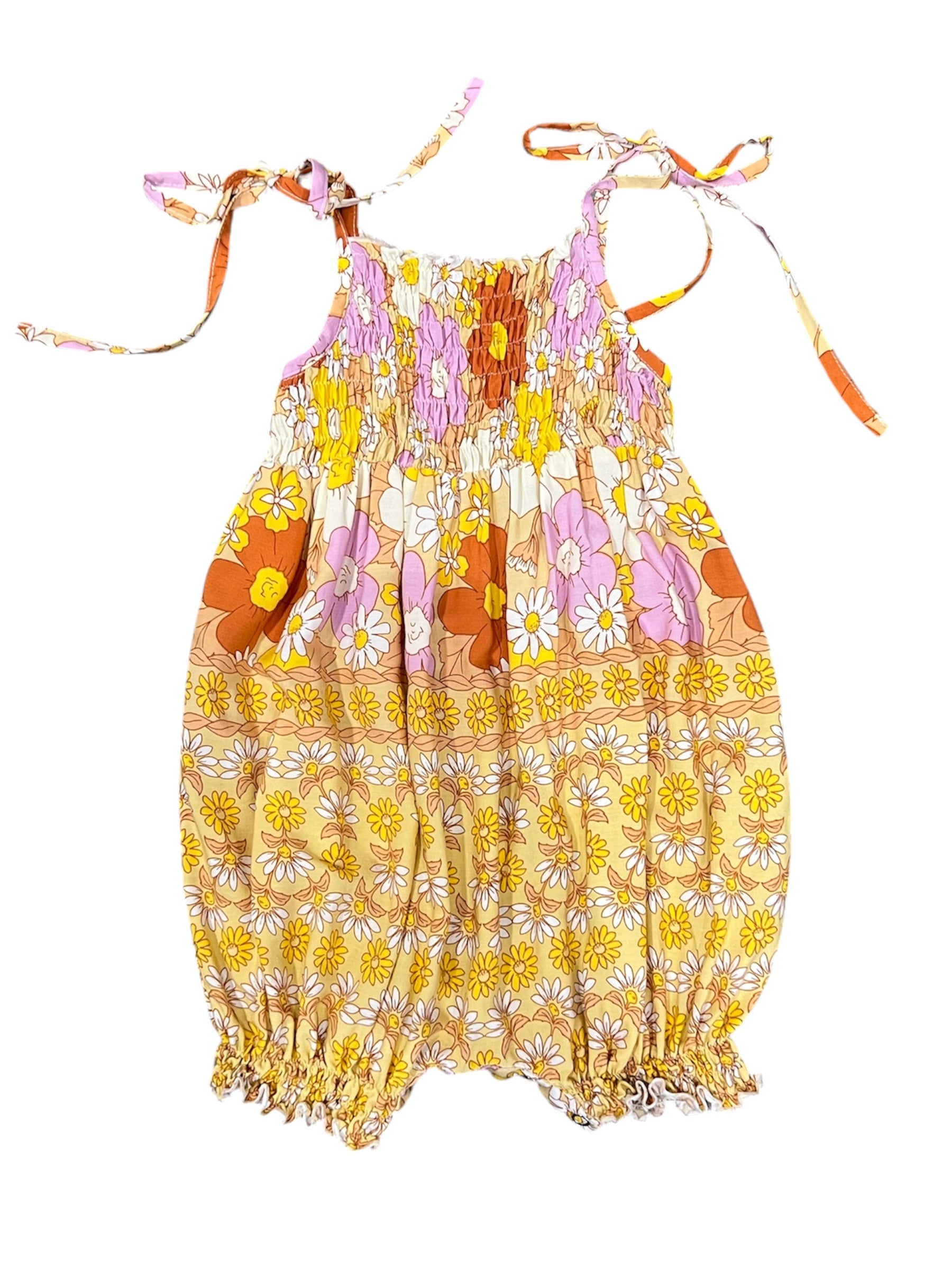 A sleeveless baby romper with a colorful floral and daisy pattern in yellow, orange, pink, and white, featuring tie-shoulder straps and a smocked bodice.