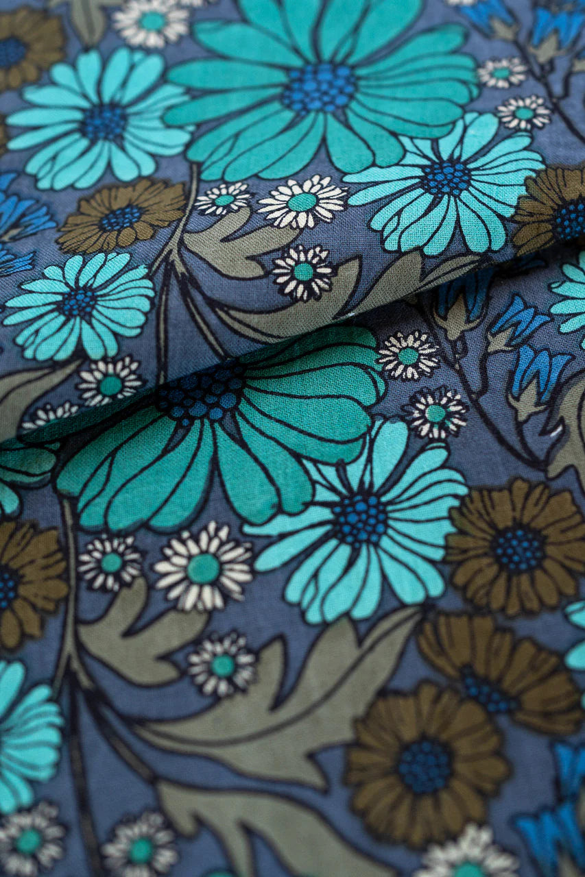 Close-up of floral fabric of Bianca Midi Dress, a blue and green flowers on a dark background